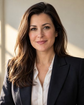 A portrait of a professional working in semiconductor design and verification, head and shoulders, square to camera, against a warm off-white wall.